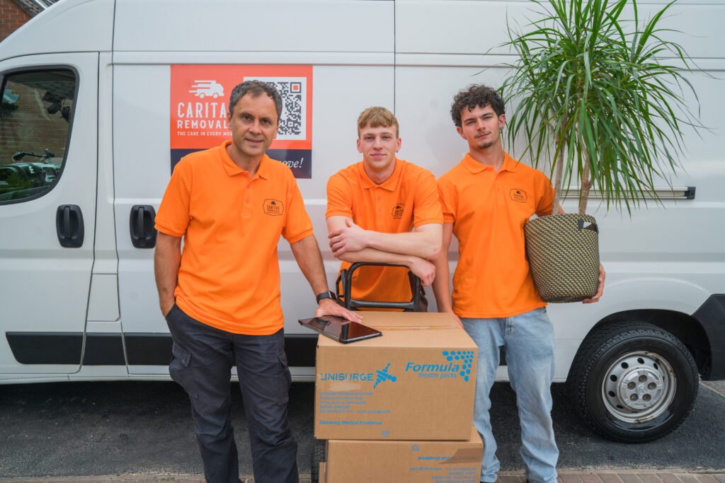 Caritas Removals team in orange uniforms standing by their removals van