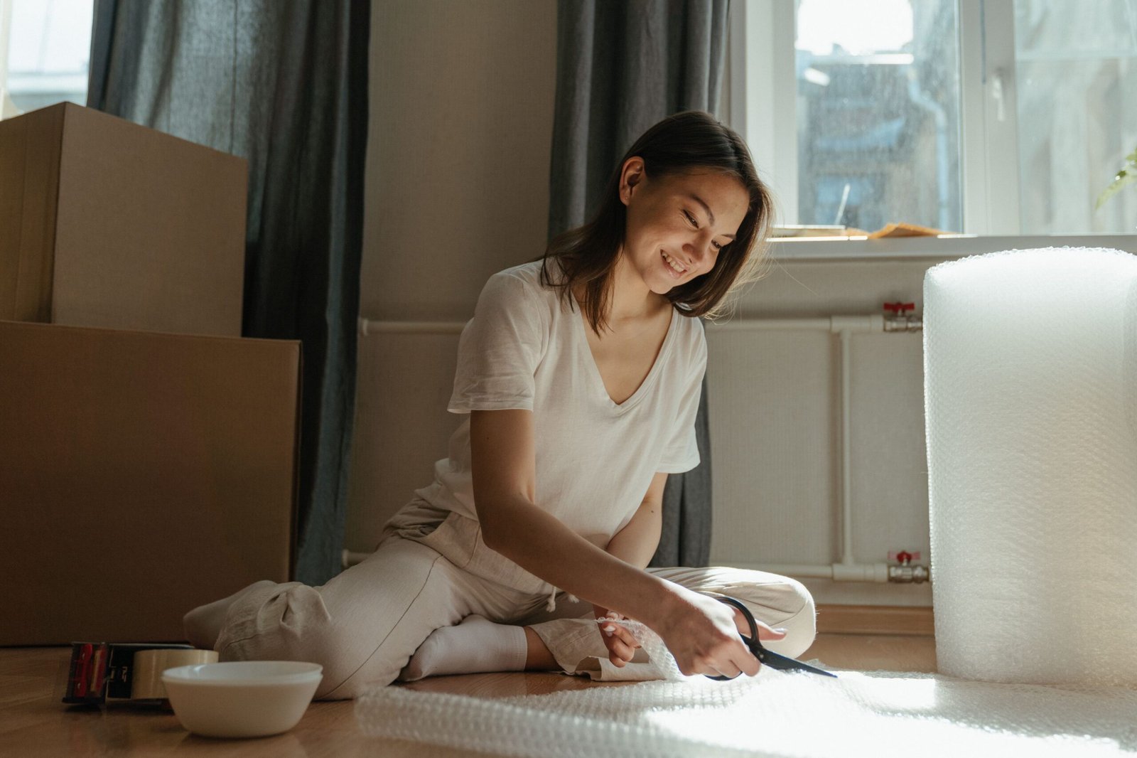 Woman cutting bubble wrap while packing for a house move
